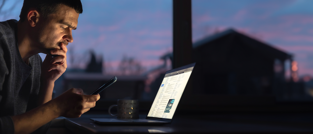 Person reviewing product screens on a phone and laptop at dusk